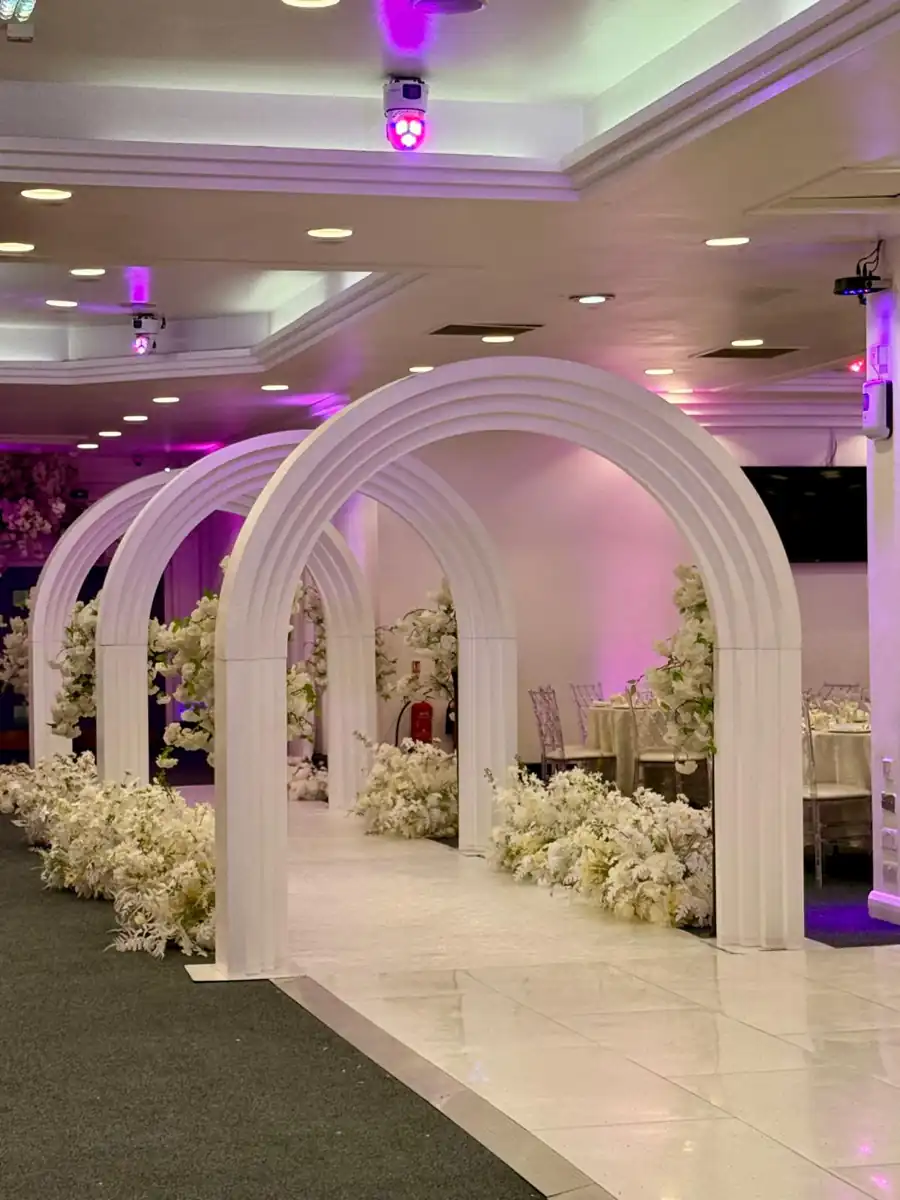 Flower-lined wedding aisle beneath white arches